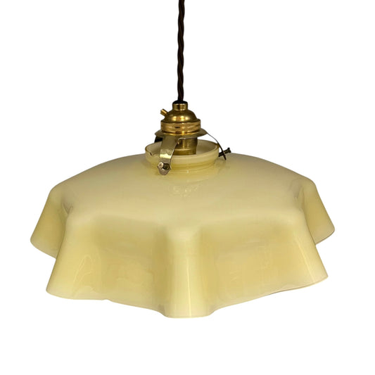 Vintage pendant light with dusky yellow glass shade and brass fixture on a white background
