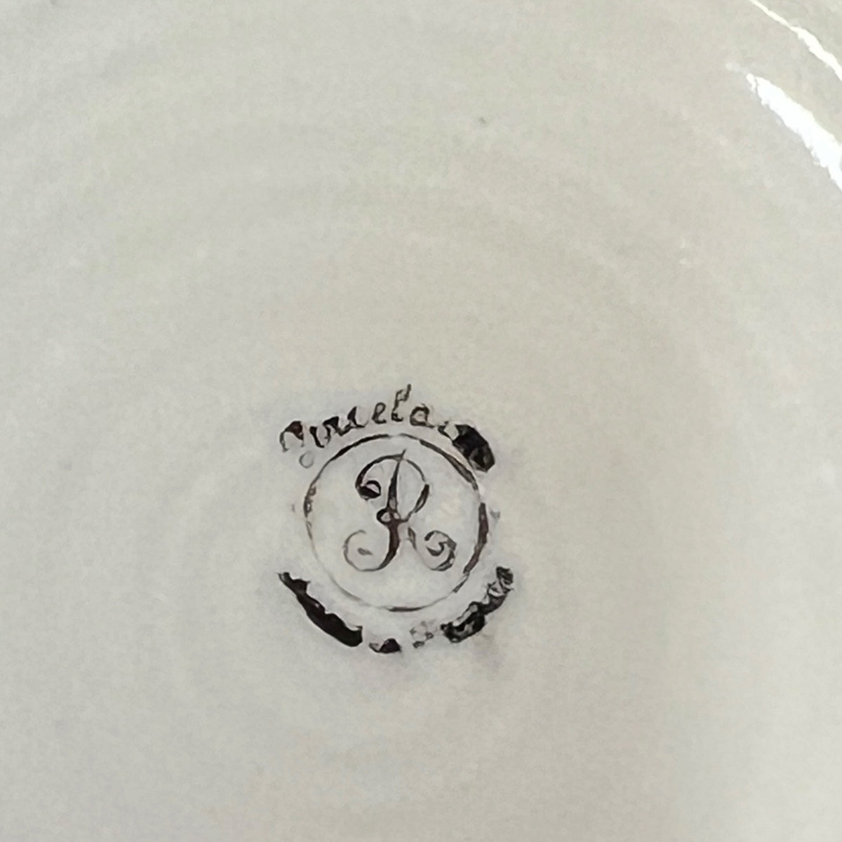 Close-up of the inside of a white ceramic pot, showing a black monogram logo with the word 'porcelain' in cursive script.