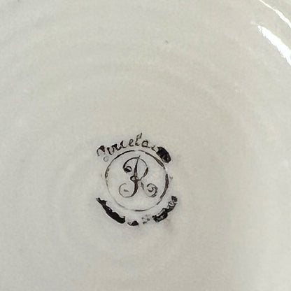 Close-up of the inside of a white ceramic pot, showing a black monogram logo with the word 'porcelain' in cursive script.