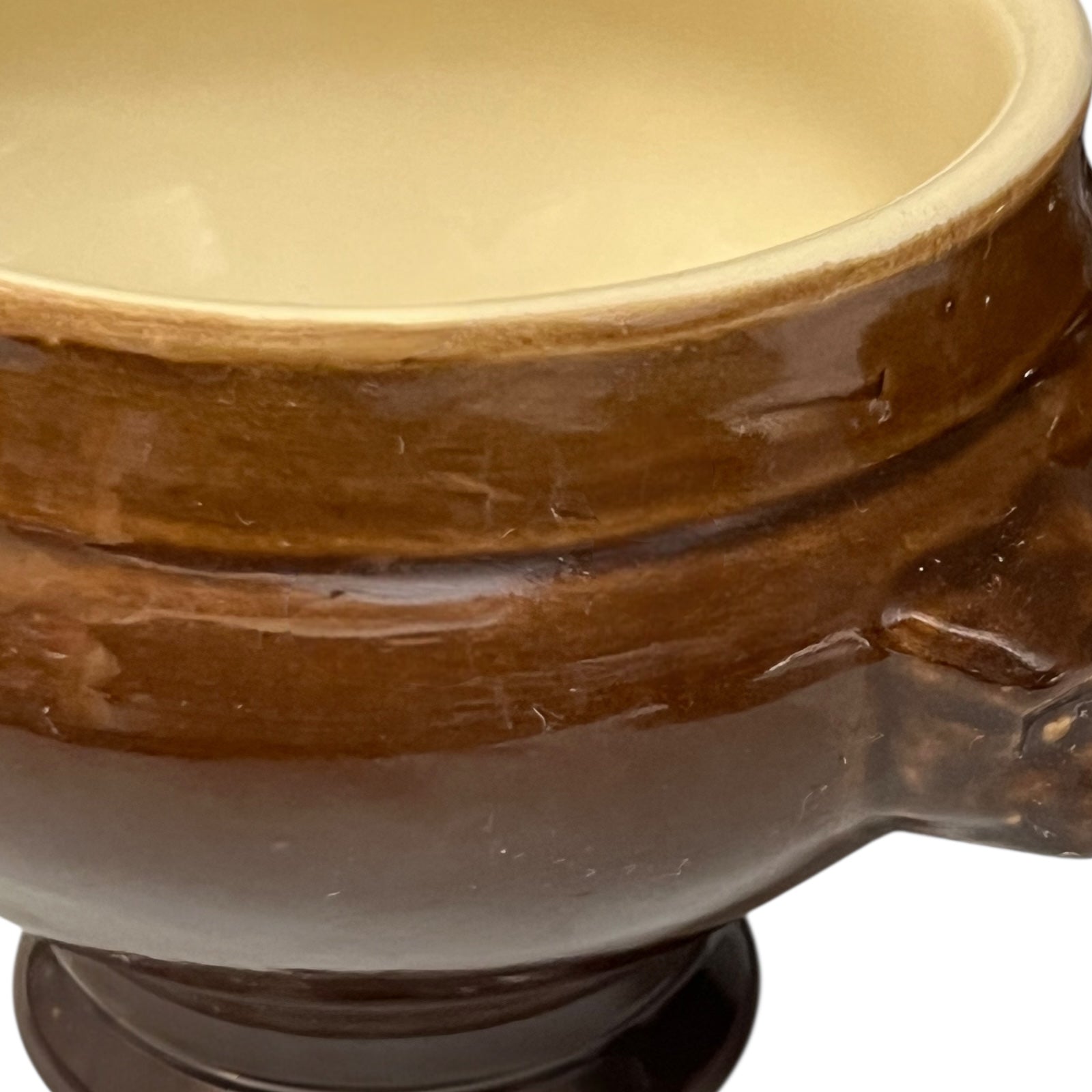 Brown ceramic bowl with decorative lion head handles on a white background