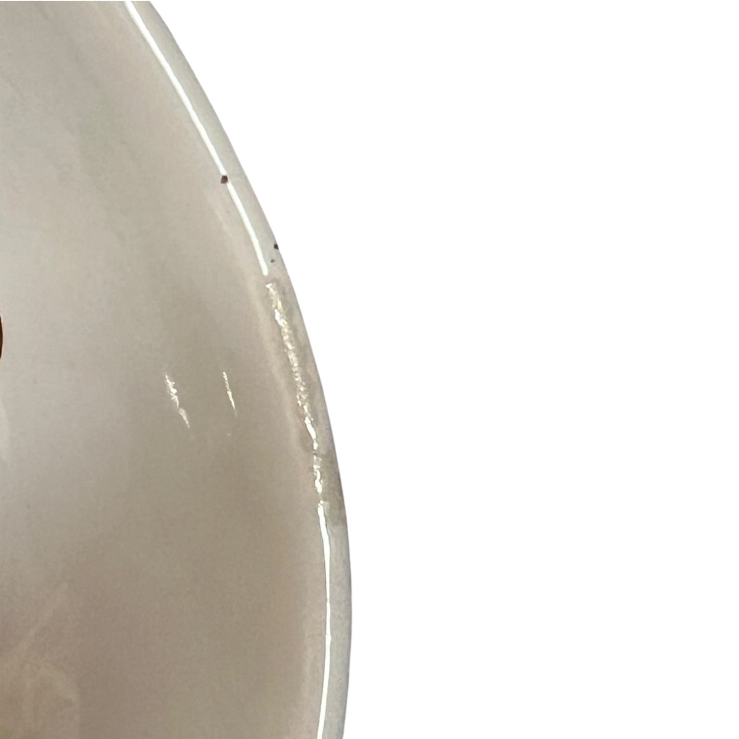 Close-up of the curved edge of a glossy off-white ceramic or porcelain bowl against a plain white background.