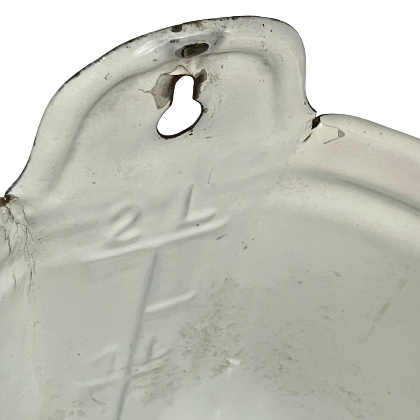 A close-up of a white measuring container with embossed measurement markings and a keyhole-shaped hole near the rim, showing some wear and dirt on a white background.