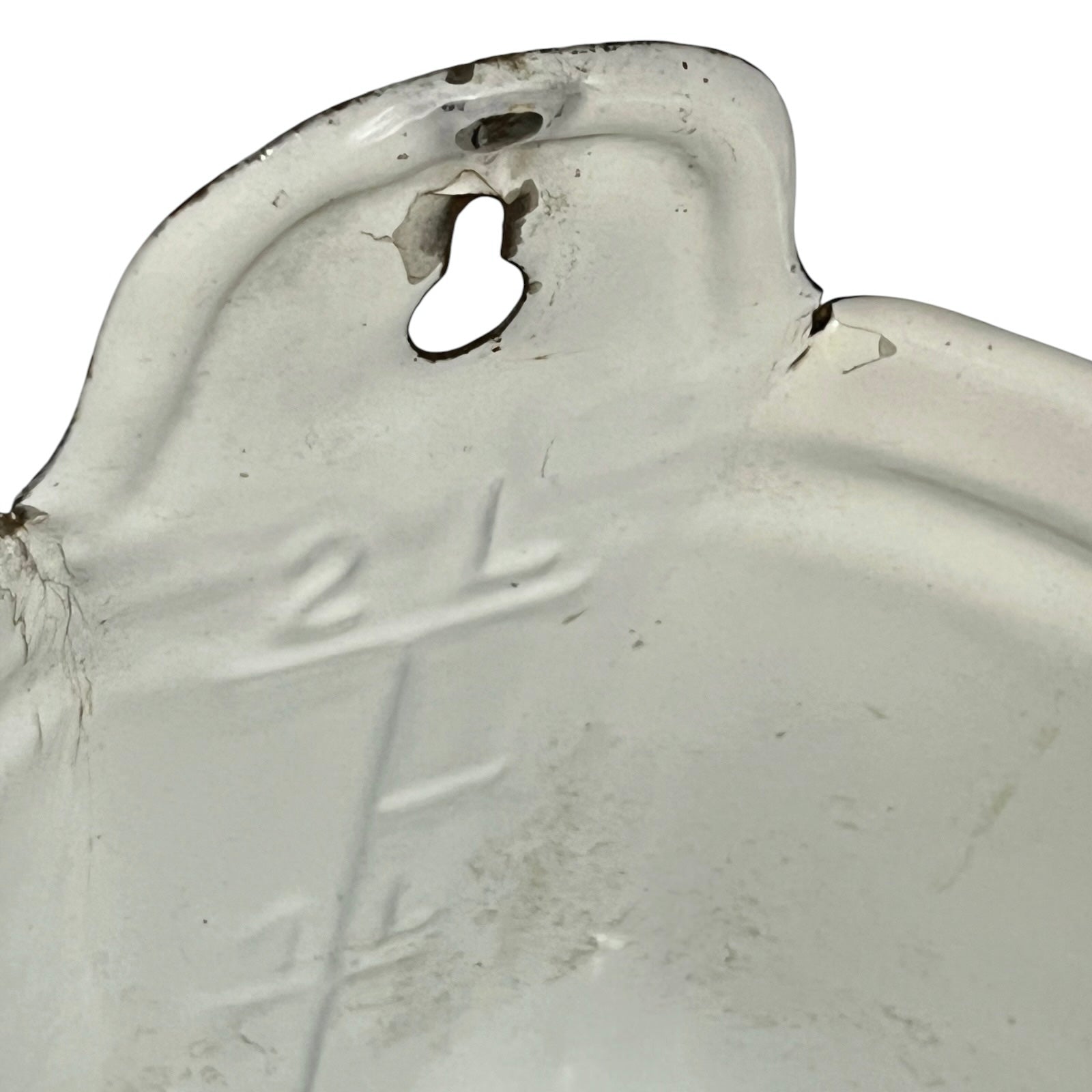 A close-up of a white measuring container with embossed measurement markings and a keyhole-shaped hole near the rim, showing some wear and dirt on a white background.