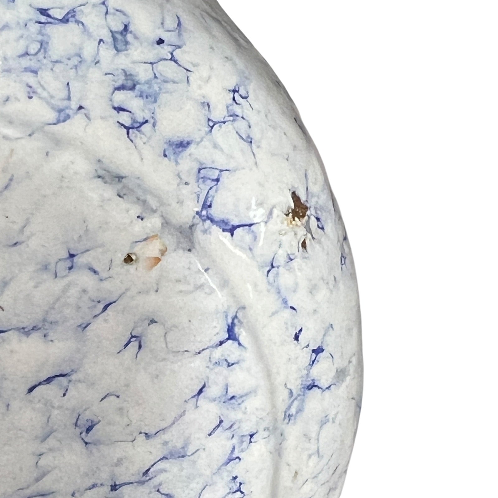 Close-up of a white enamel surface with blue marbled veining and a few small brown specks, shown against a white background.