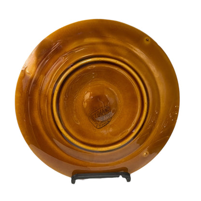 Brown ceramic plate on a stand with visible branding