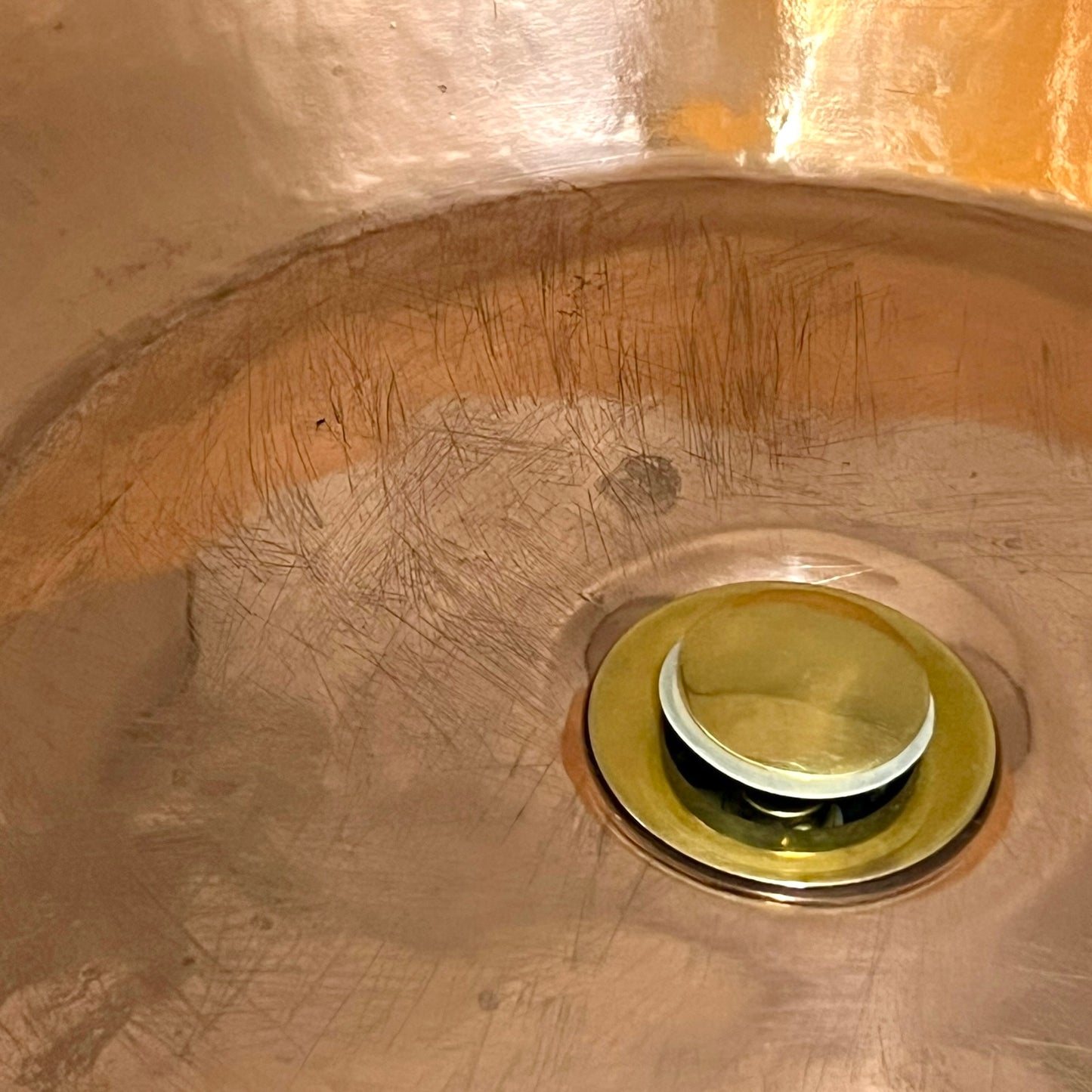 Close-up of a sink drain with a gold-colored stopper