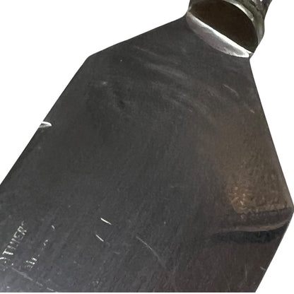 A close-up of a dark metal blade or tool head with a polished silver collar, shown against a plain white background.