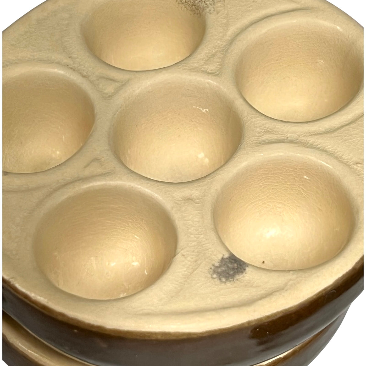 Close-up of a ceramic six-dish plate with a glossy cream-colored glazed interior and a dark brown glazed rim.
