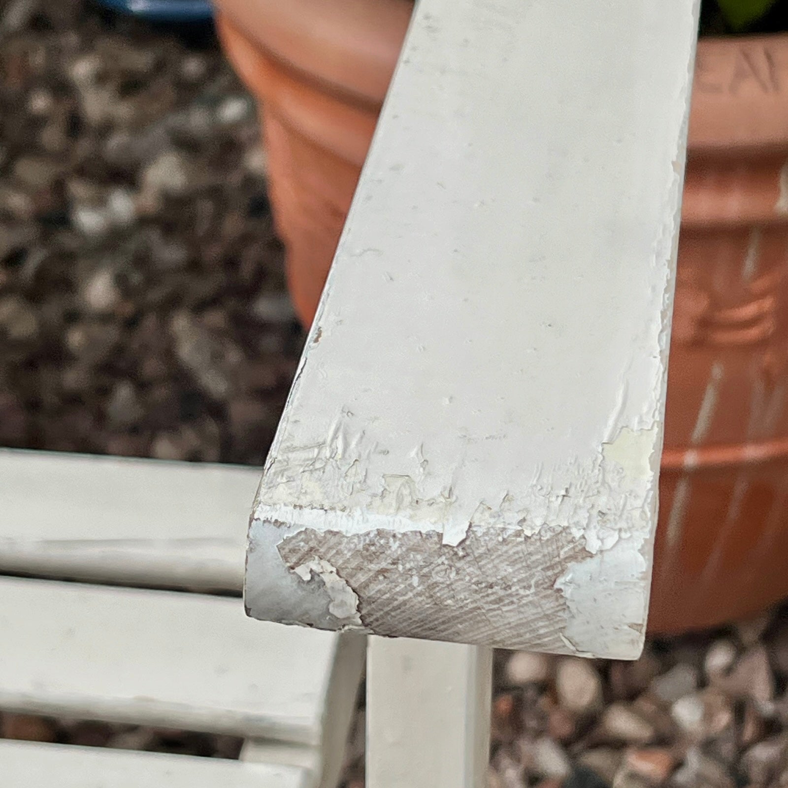Close-up detail of French wooden slatted chairs, highlighting their condition in an outdoor setting.