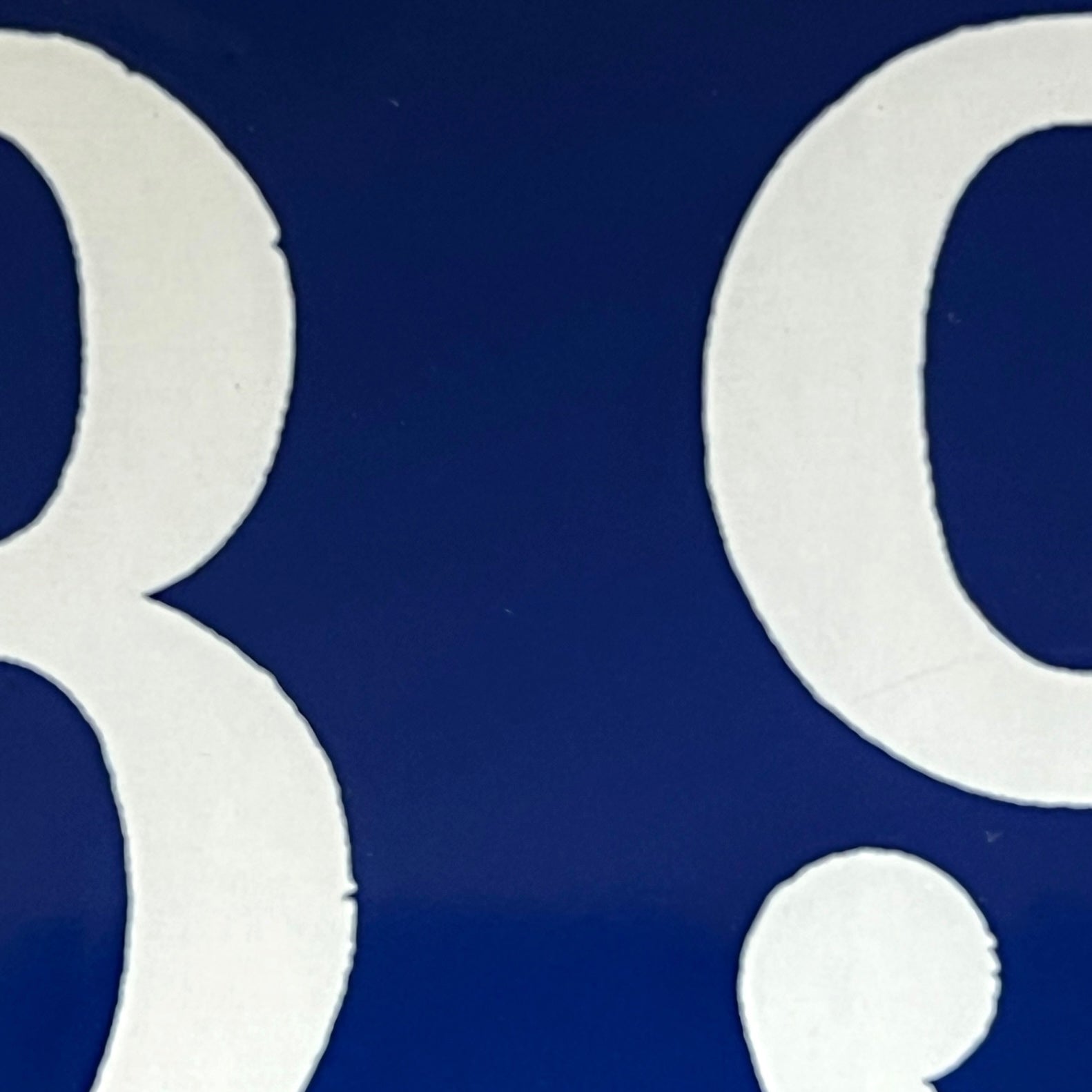 A close-up of a blue surface with large white numerals or letters, showing partial digits 89