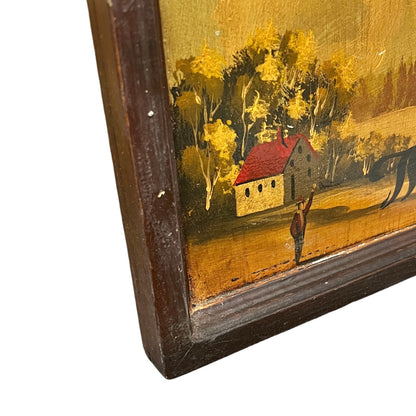 Close-up corner view of a framed rustic landscape painting showing a small house with a red roof, yellow trees, and a dark brown wooden frame on a white background.