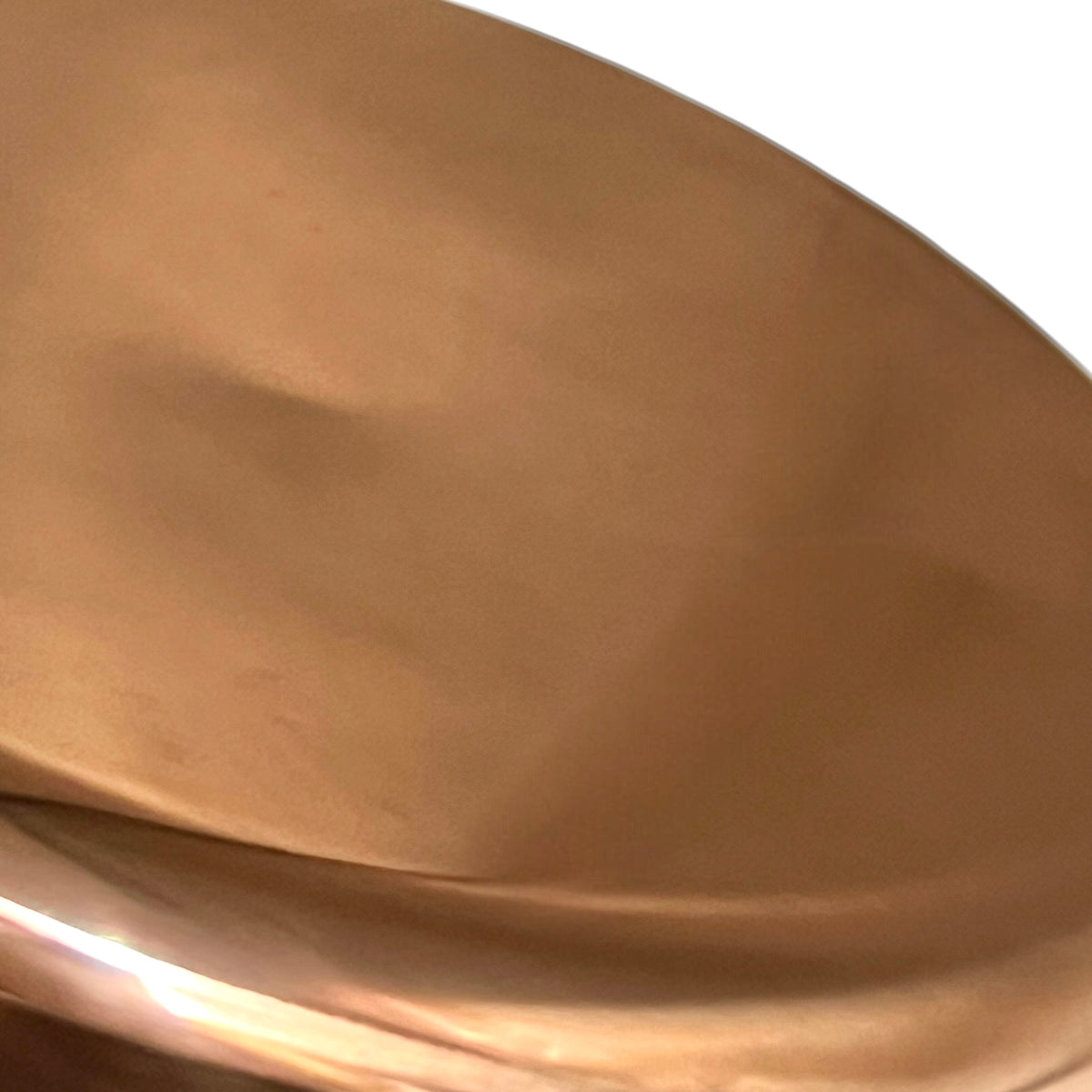 Close-up of a smooth, metallic copper-colored surface with a warm bronze sheen and soft reflections.