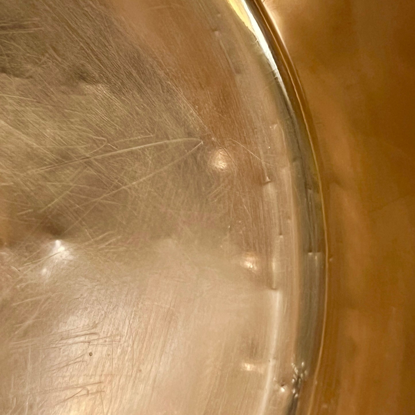 Close-up of the interior bottom of a copper sink with some scratches.