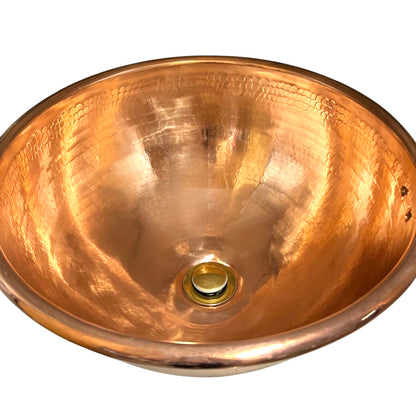A hammered copper bathroom sink basin with a polished brass drain, shown from a top-down perspective against a white background.