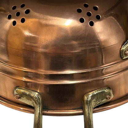 Close up of a copper colander with on a white background
