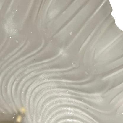 Close up of a glass lampshade and brass fittings on a white background