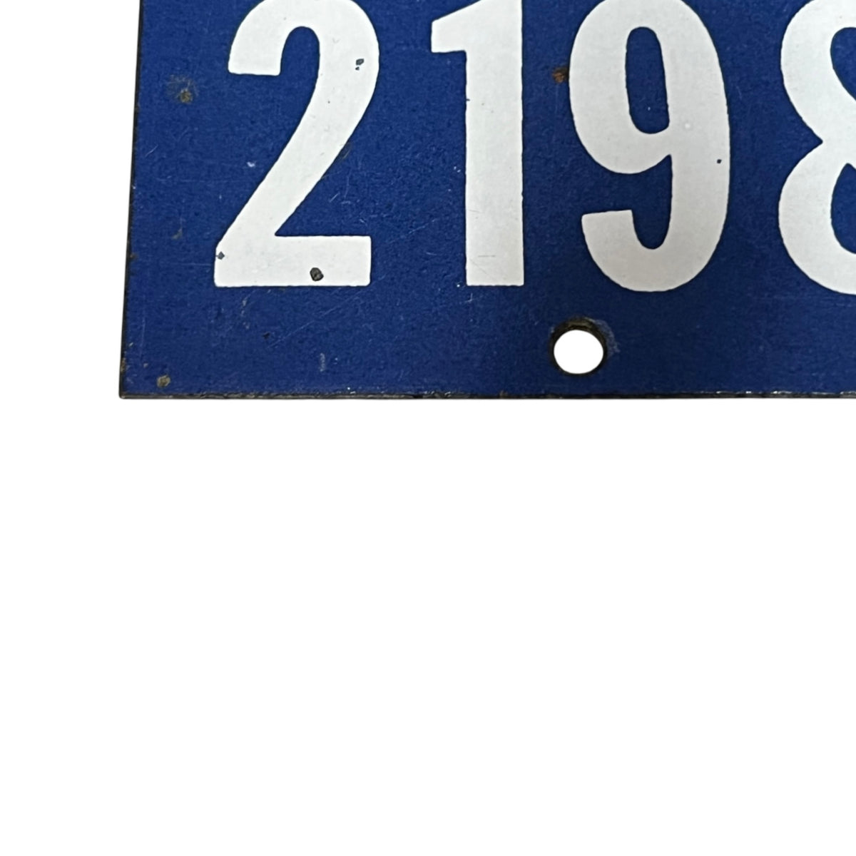 A close-up of a blue rectangular sign or plate with large white numerals '2198' and a small round hole near the bottom center, shown against a white background.
