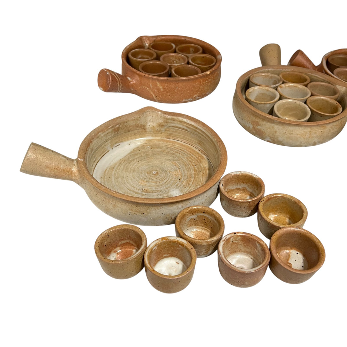 A set of handmade terracotta snail plates , and multiple small cups, arranged on a plain white background.