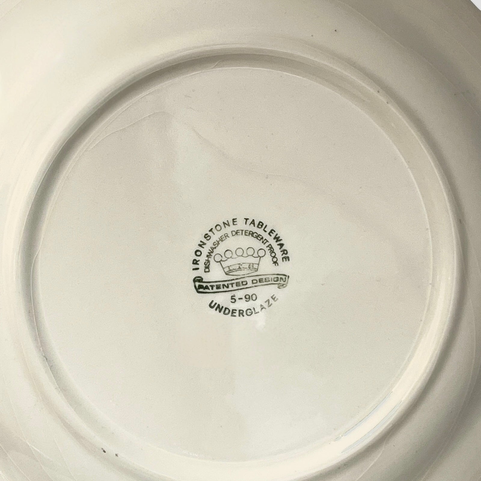 Close-up of a ceramic plate with branding and text on the base.