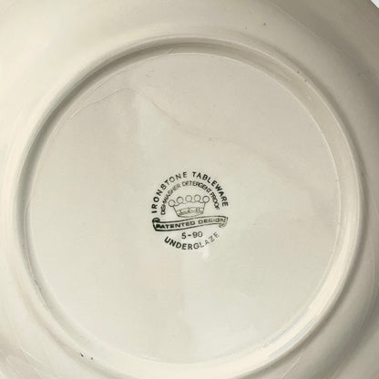 Close-up of a ceramic plate with branding and text on the base.