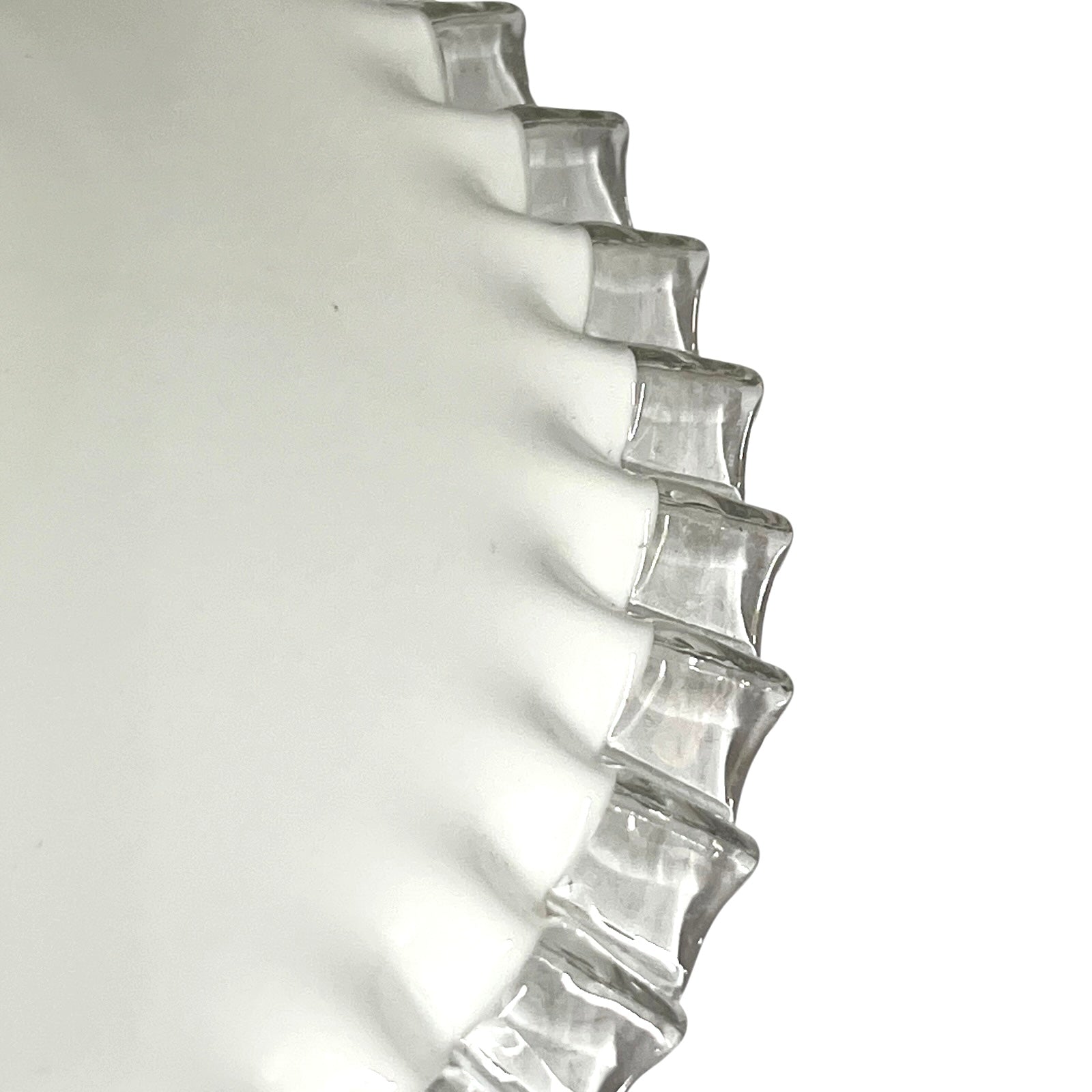 A close-up of a clear glass lampshade with a wavy, scalloped rim, photographed against a plain white background.