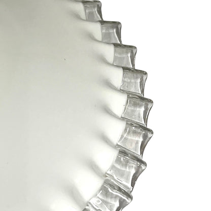 A close-up of a clear glass lampshade with a wavy, scalloped rim, photographed against a plain white background.