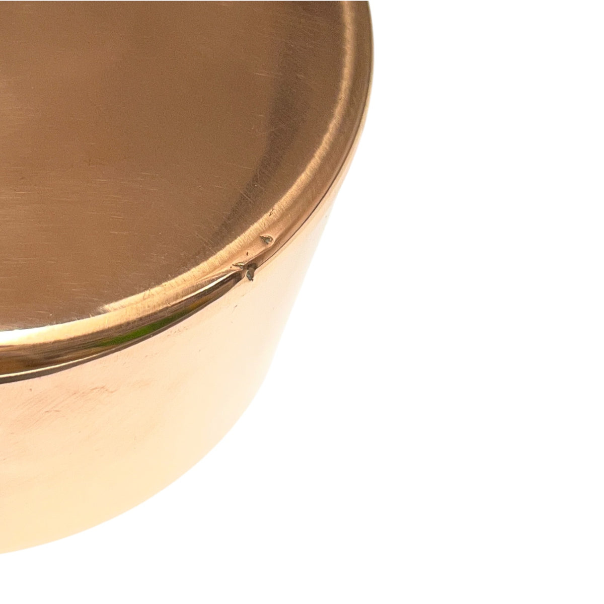 Close-up of a metallic copper-colored pot or container corner on a plain white background.