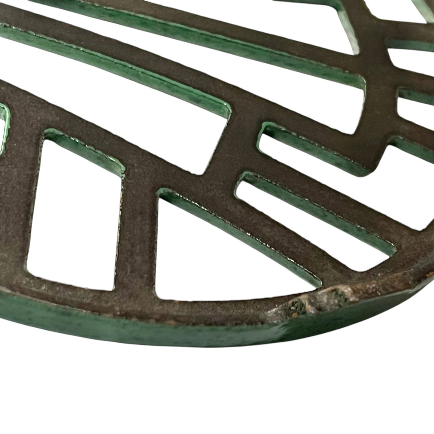 Close up of a green vintage French cast iron enamelled pan trivet on a white background