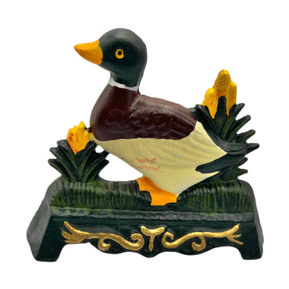 Cast iron duck doorstop on a decorative stand with a white background
