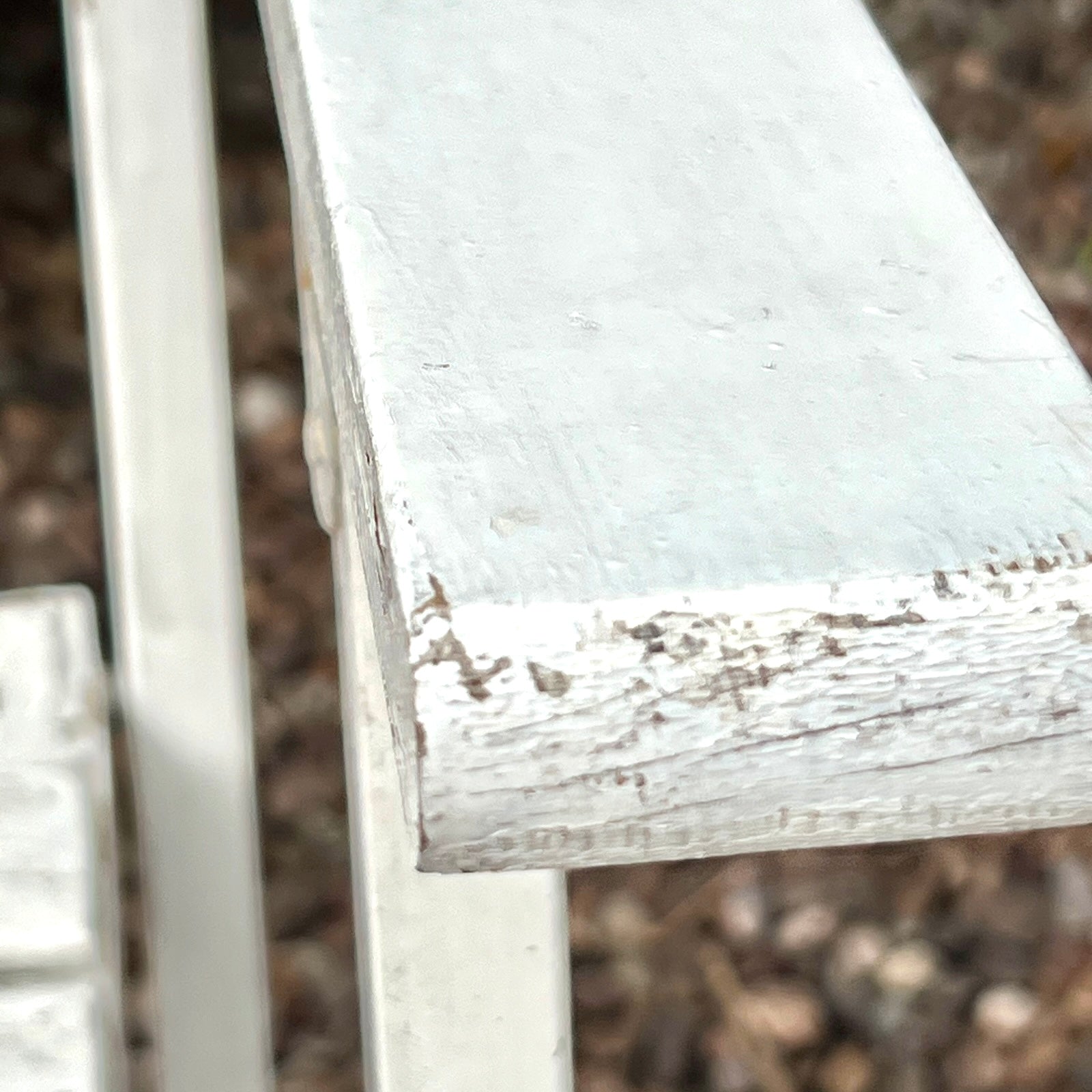 Close-up detail of French wooden slatted chairs, highlighting their condition in an outdoor setting.