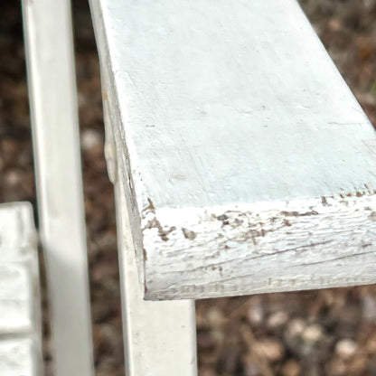 Close-up detail of French wooden slatted chairs, highlighting their condition in an outdoor setting.