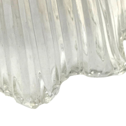 Close-up of a clear glass vase with ribbed texture on a white background
