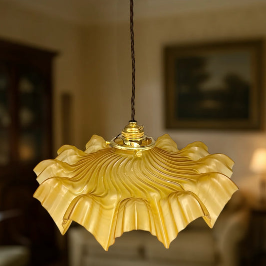 Amber coloured vintage French  pendant light with a scalloped design  with a blurred lounge in the background