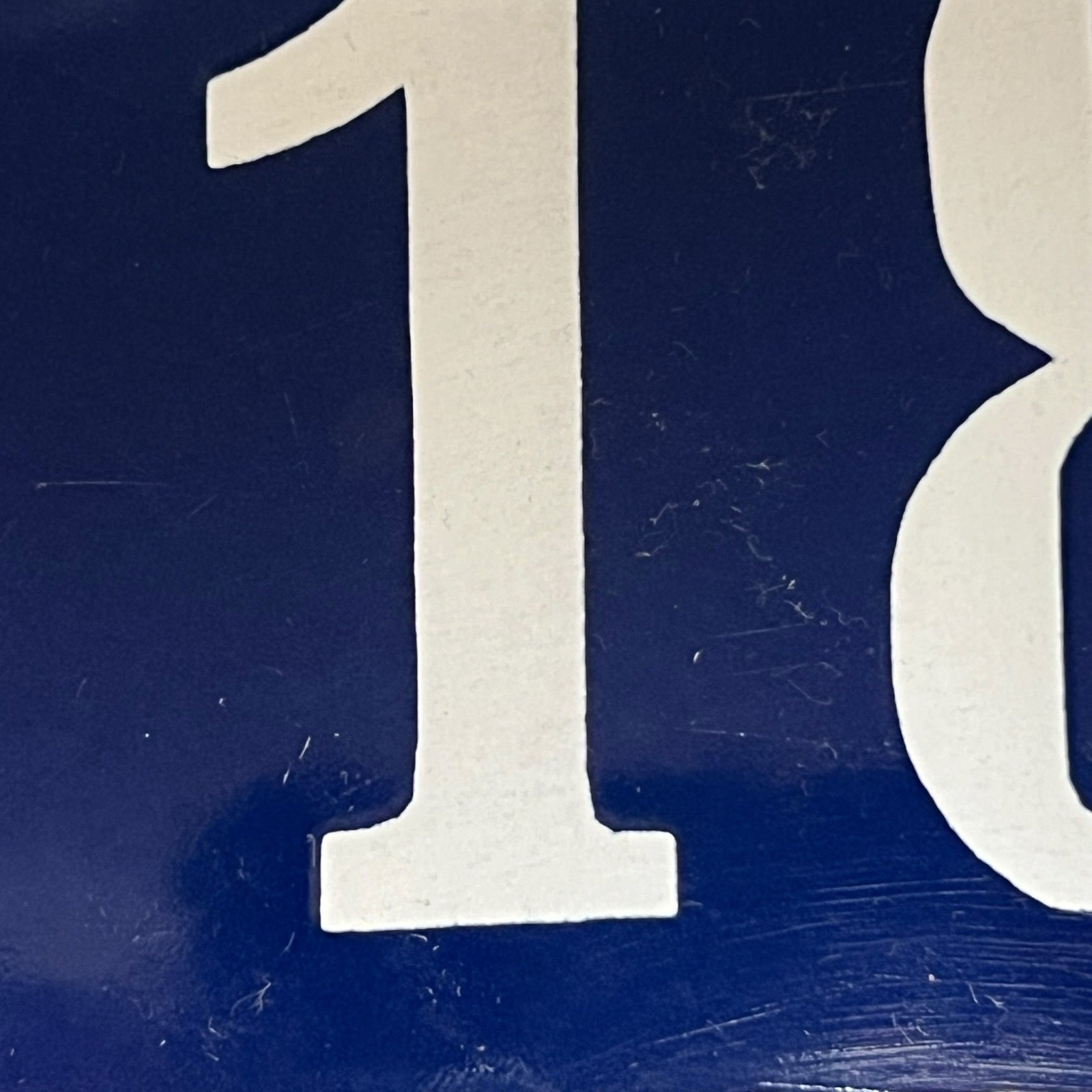 Close-up of a blue sign with white number 118 on a white background
