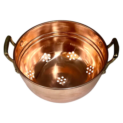 A copper pot with two side handles and perforated cutouts on the bottom, shown on a plain white background.