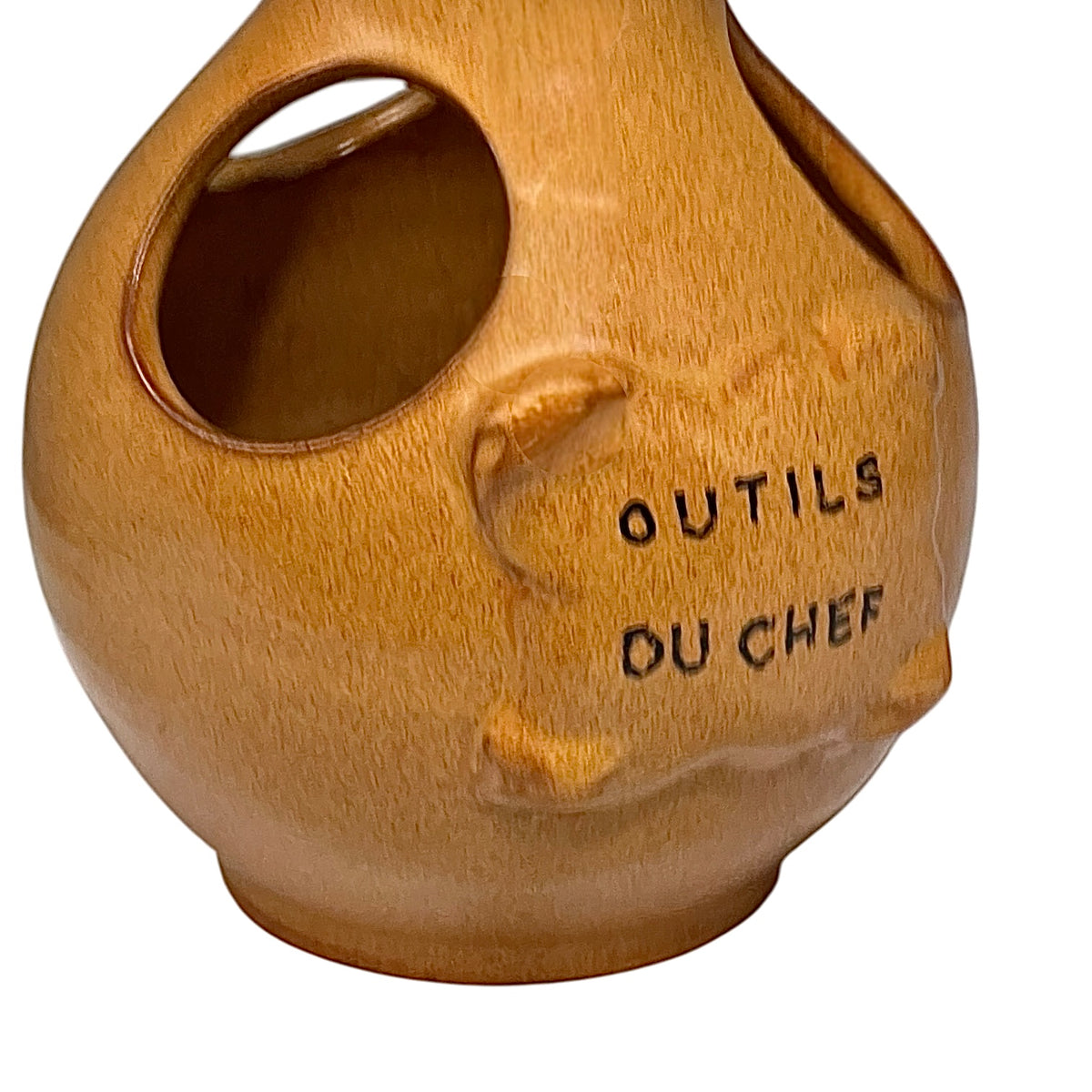 side view of a vintage French ceramic kitchen utensil holder with a honey-brown mottled glaze, rounded body and two large angled side openings. Raised front plaque inscribed Outils du Chef, meaning Chef's Tools. Traditional rustic French country kitchen pottery measuring 18.5 cm high, sourced from a French brocante and shown on a plain white background 