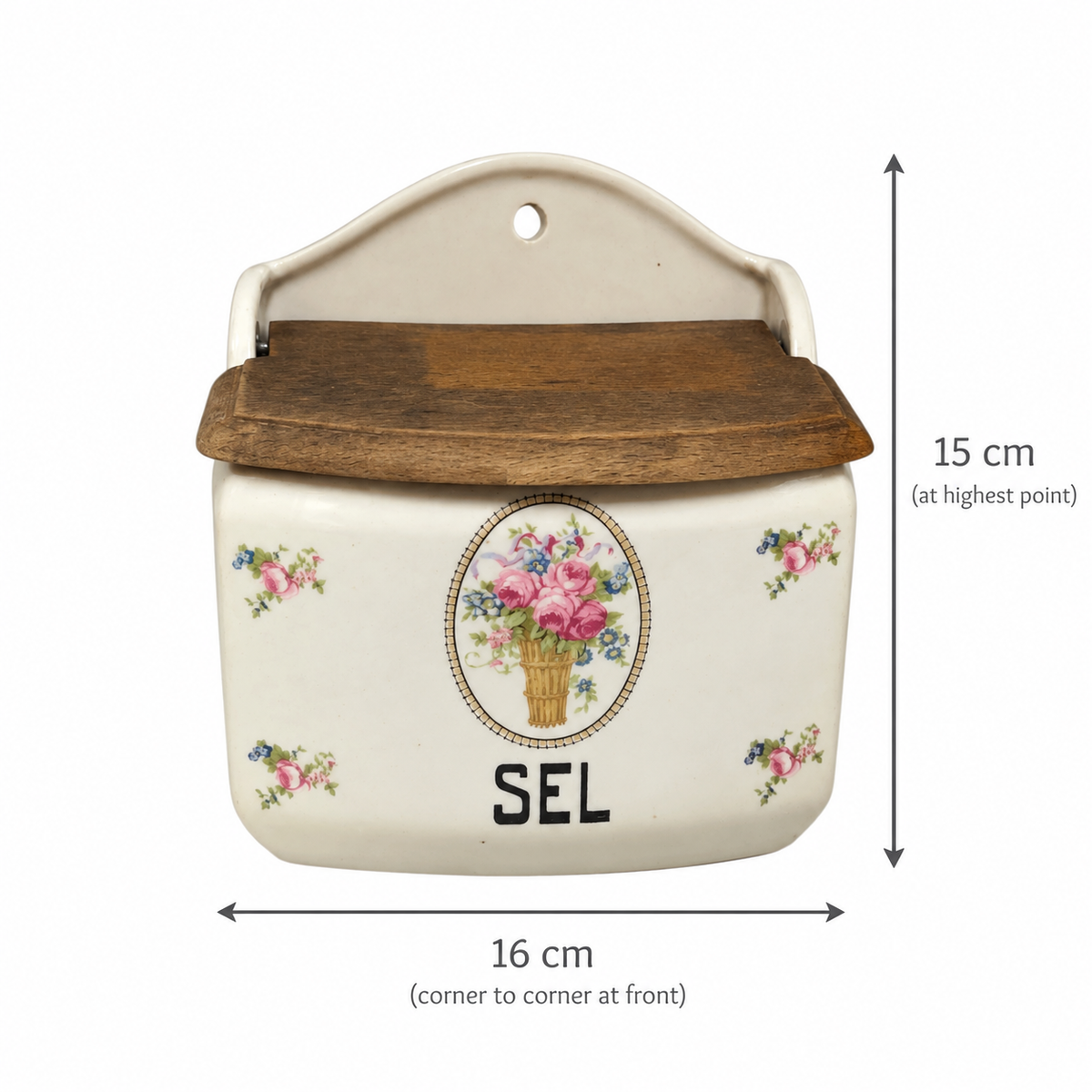 An off-white ceramic wall-mounted storage box with a dark brown wooden lid, decorated with a floral bouquet design and the letter 'SEL'. Black dimension lines and text indicate its height is 15 cm and width is 16 cm.