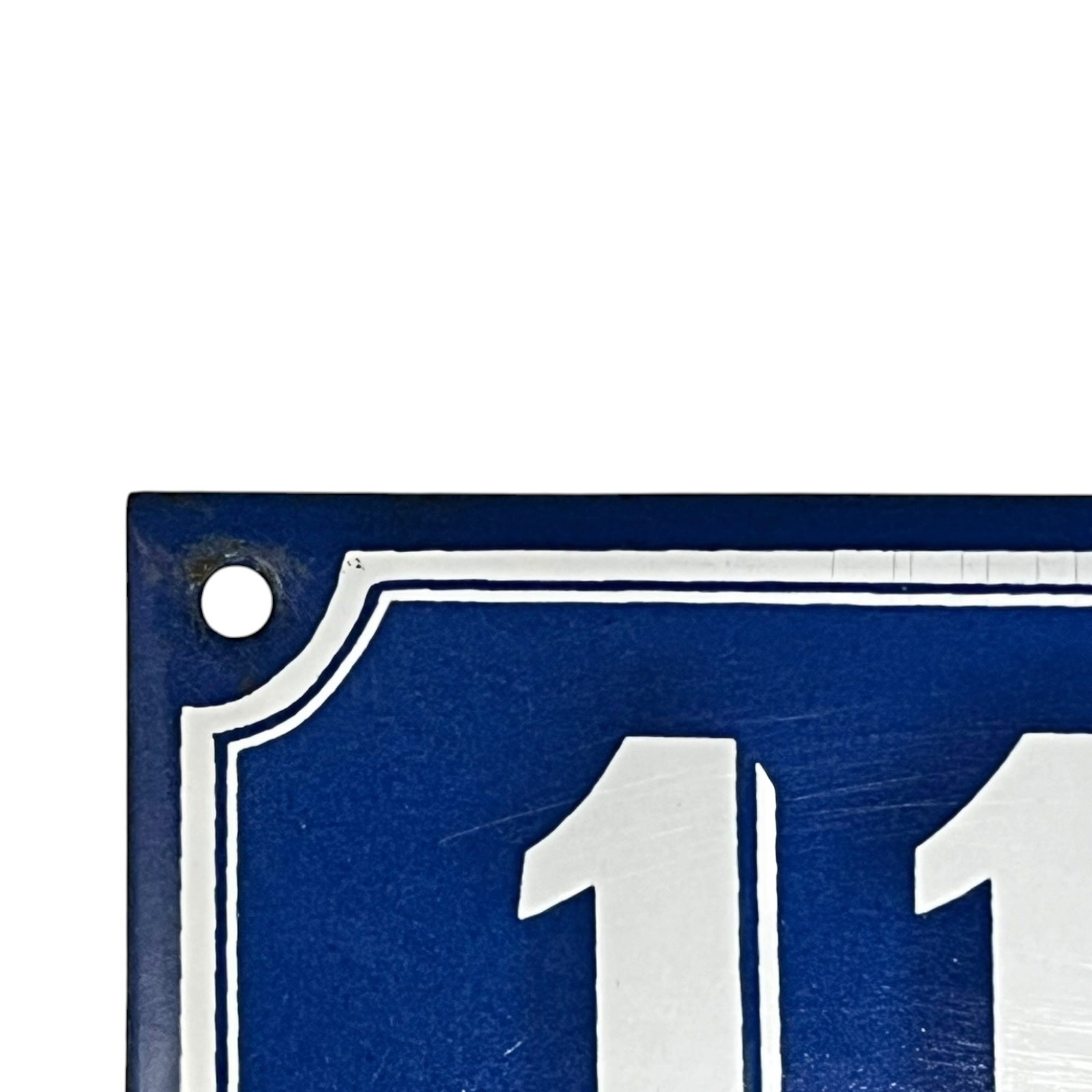 Close up of a blue French metal house number plate with white numbers '111' on a white background