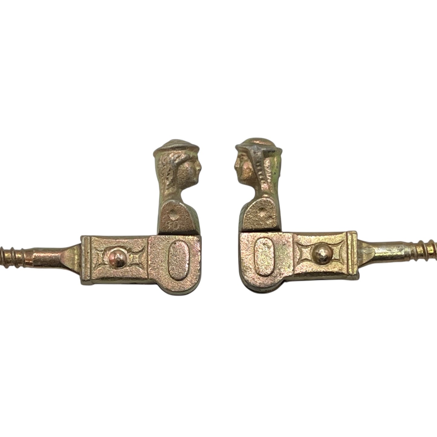 Two brass coloured French decorative shutter brackets on a white background