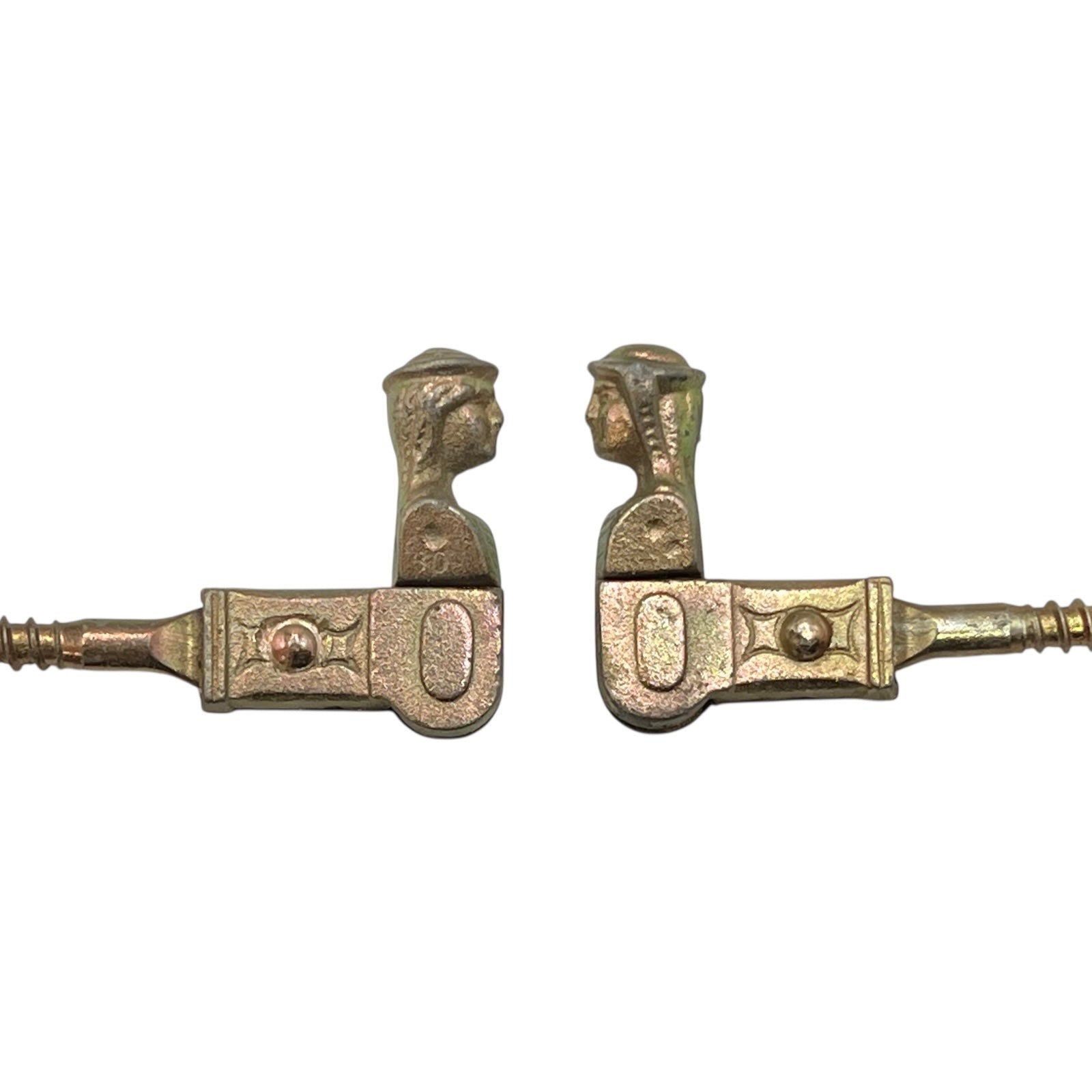 Two brass coloured French decorative shutter brackets on a white background