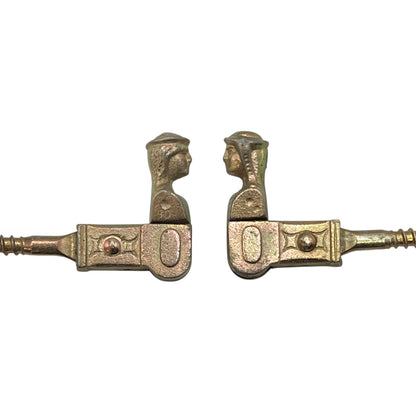 Two brass coloured French decorative shutter brackets on a white background