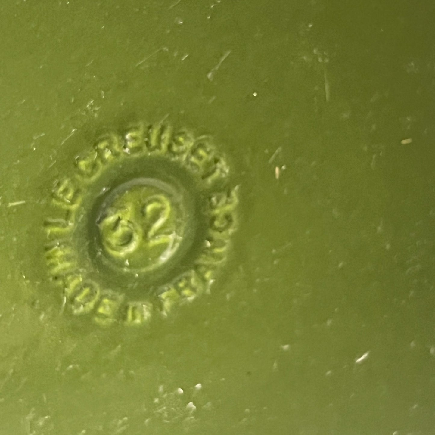 Close-up of a green Le Creuset cast iron skillet on a white background 
