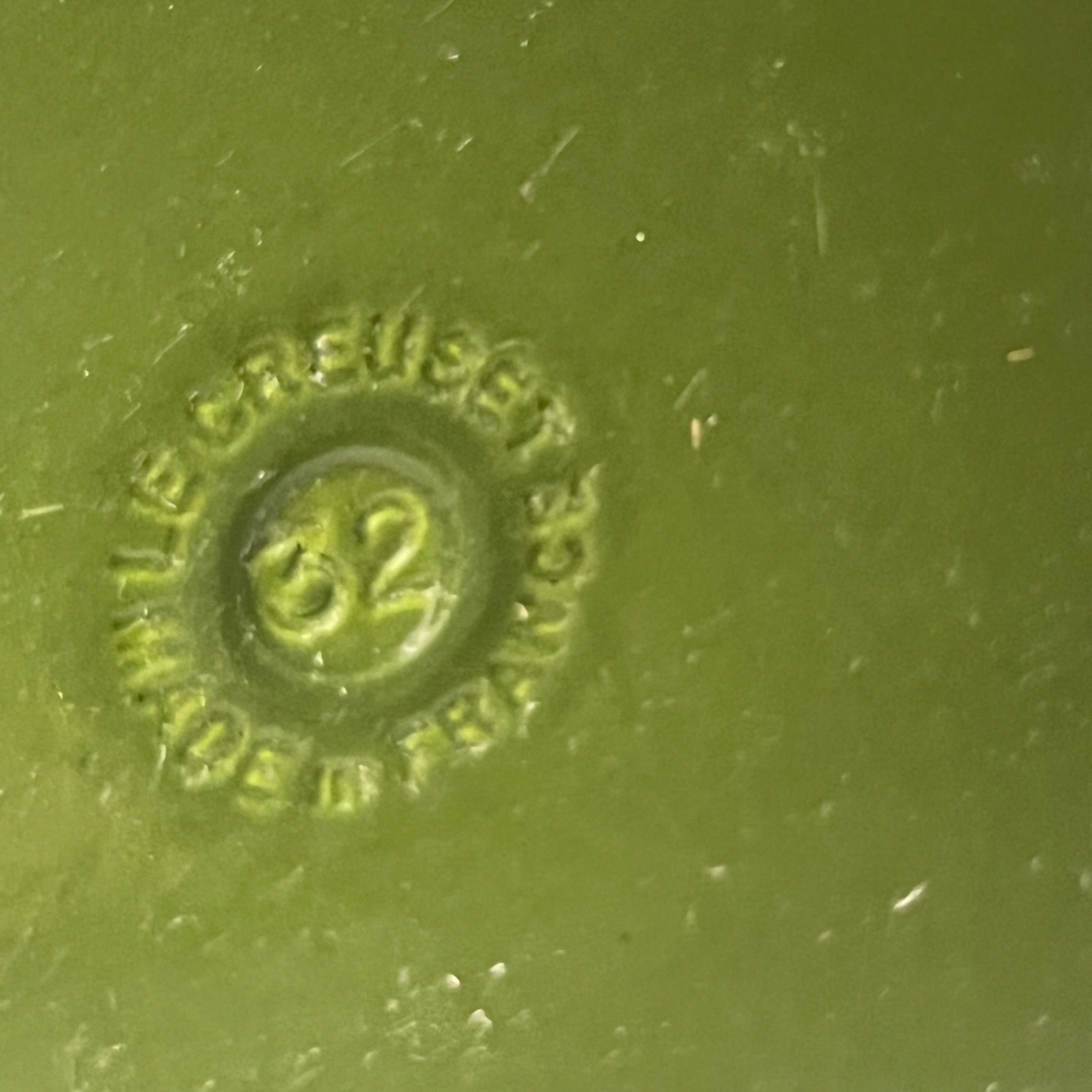 Close-up of a green Le Creuset cast iron skillet on a white background 
