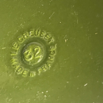 Close-up of a green Le Creuset cast iron skillet on a white background 