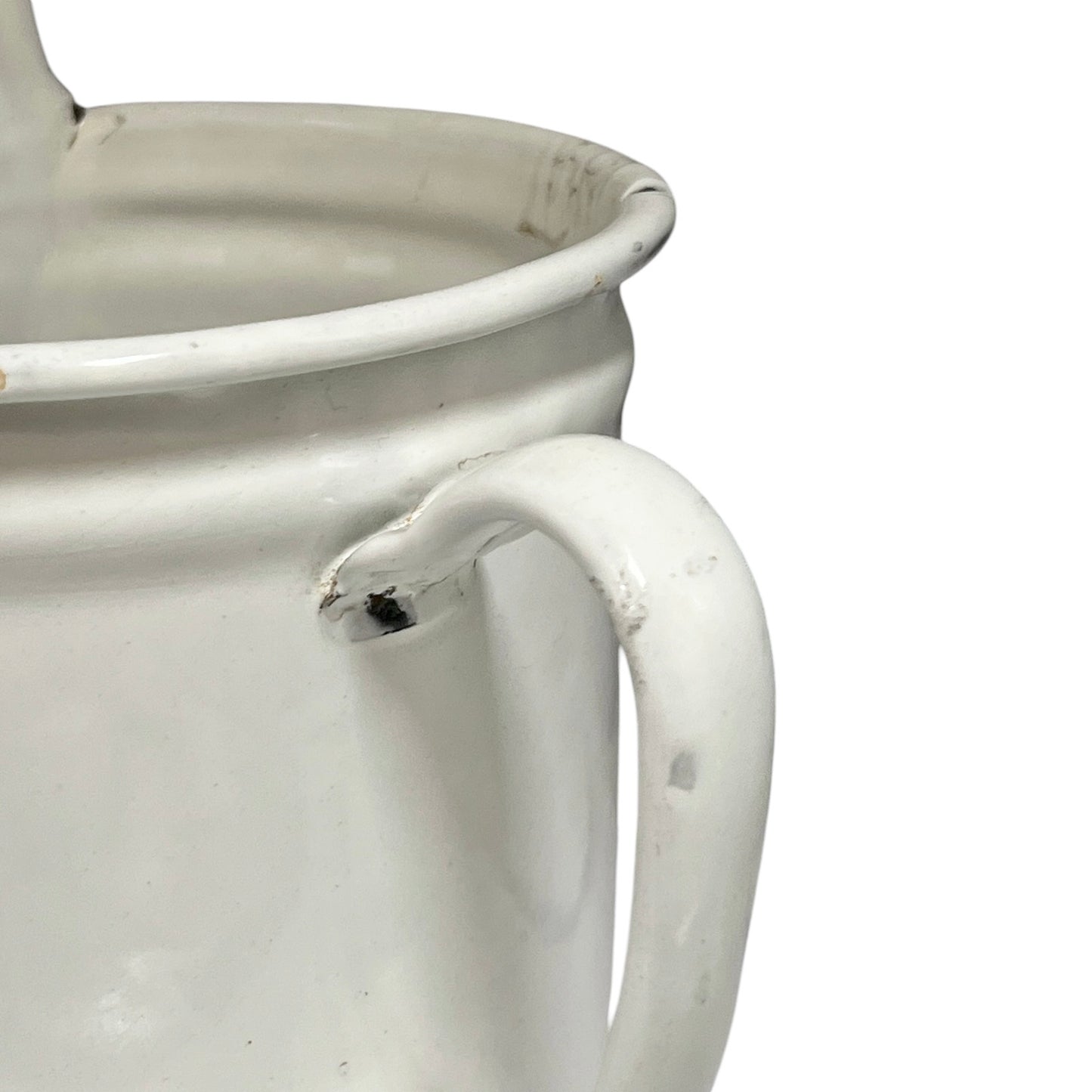 A close-up of a white enamel pitcher with a distressed, vintage finish showing minor scuffs and wear on the handle and rim, set against a plain white background.