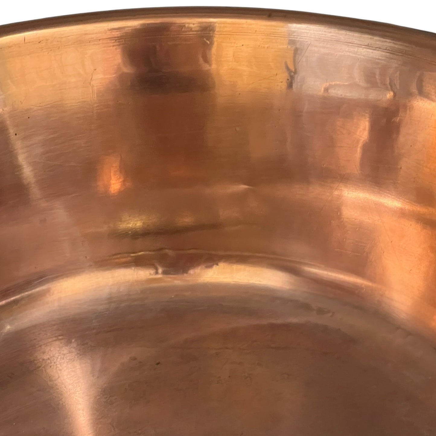 Close-up of the interior of a copper pot or pan, showing a warm metallic copper-brown reflective surface.