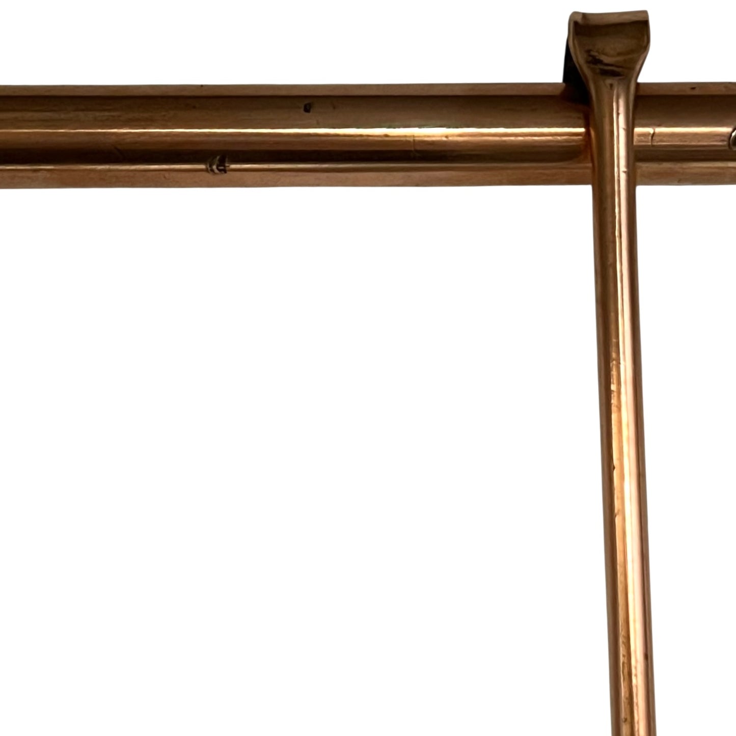 Close up of 3 copper utensils on a copper hanging bar on a white background