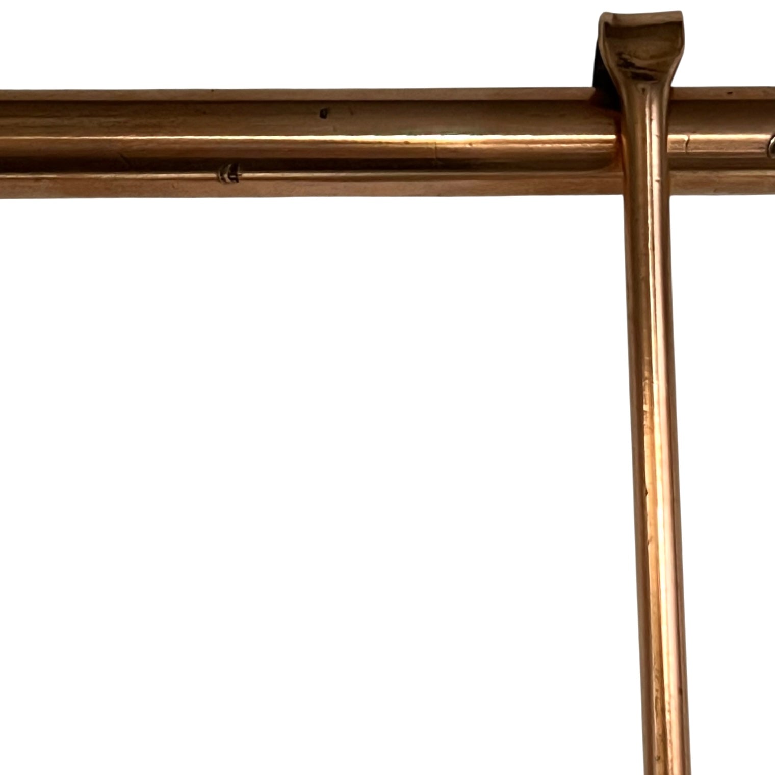 Close up of 3 copper utensils on a copper hanging bar on a white background