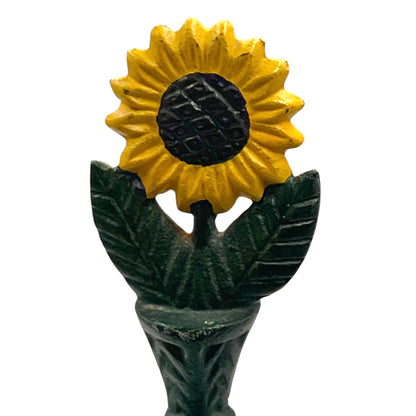 Decorative sunflower top with yellow petals and green leaves sitting on a kitchen roll holder on a white background