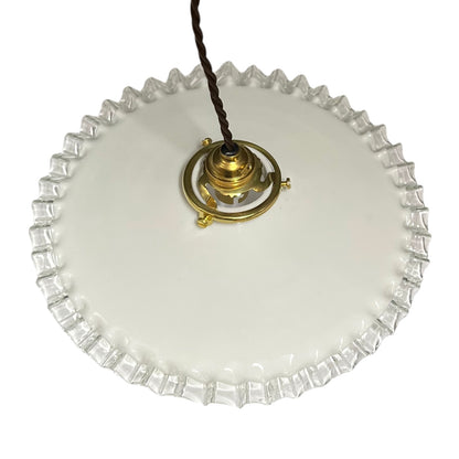 A vintage white glass ceiling light shade with a fluted, scalloped edge and a brass central fixture, suspended by a dark brown cord against a white background.
